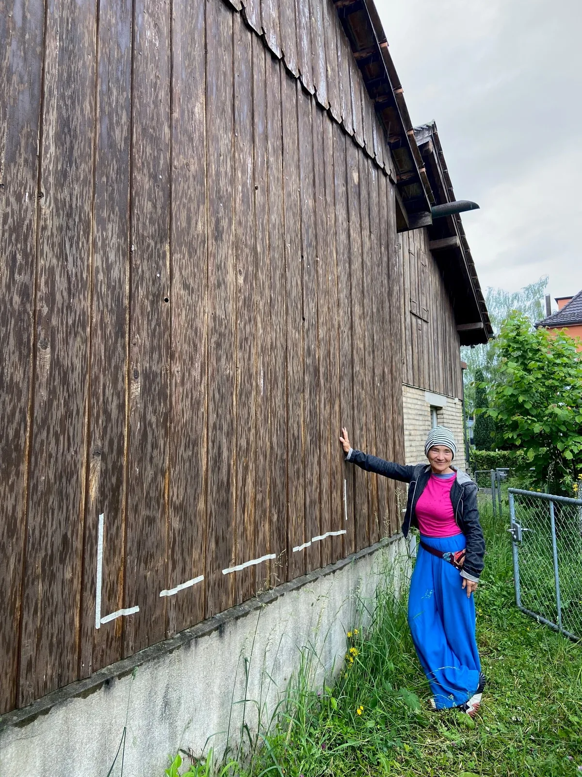 Lilian Frei vor einer Häuserwand aus Holz.